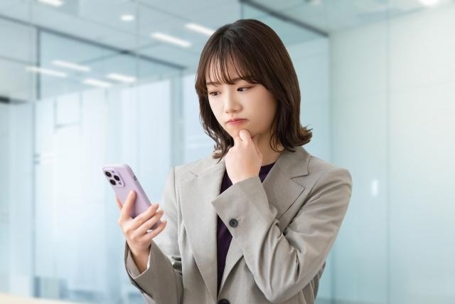 スマホを見ながら考えている女性