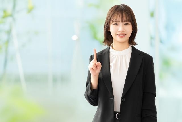 人差し指を立てて案内する笑顔の女性