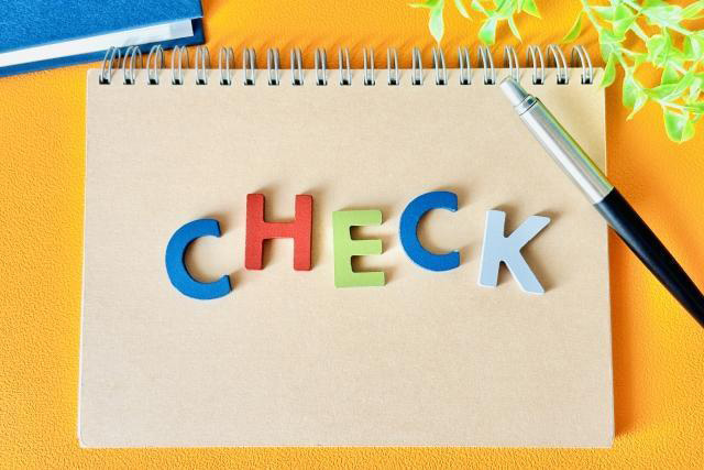 リングノートに描かれたチェックの文字とペン