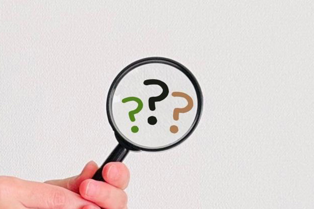 ？が書かれた虫眼鏡を持つ手